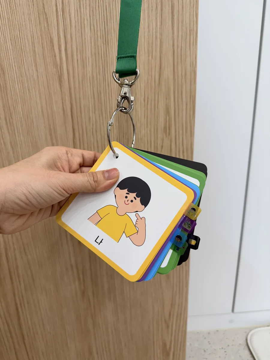 고리와 목걸이 줄에 끼운 휴대용 AAC 상징카드, 맨 앞 카드는 '나'